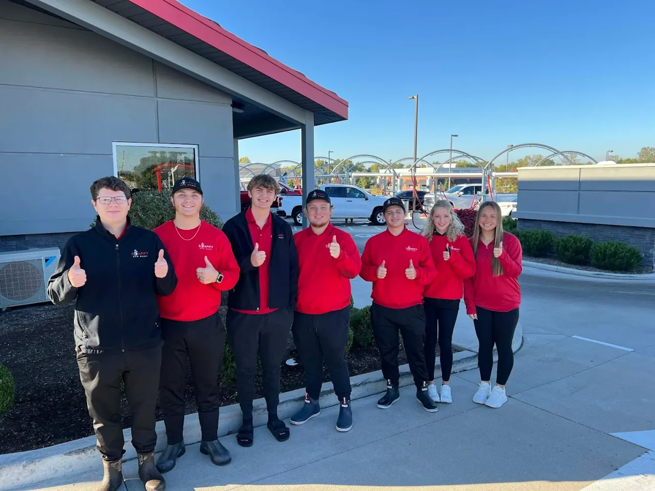 The Soapify St. Charles team out front of the wash, giving a thumbs up under a clear blue sky